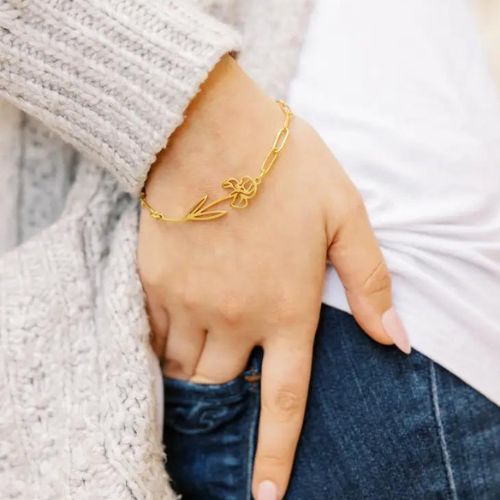 Una sofisticada pulsera de acero inoxidable con flores de nacimiento que añaden un toque de refinamiento a cualquier conjunto. - Oro